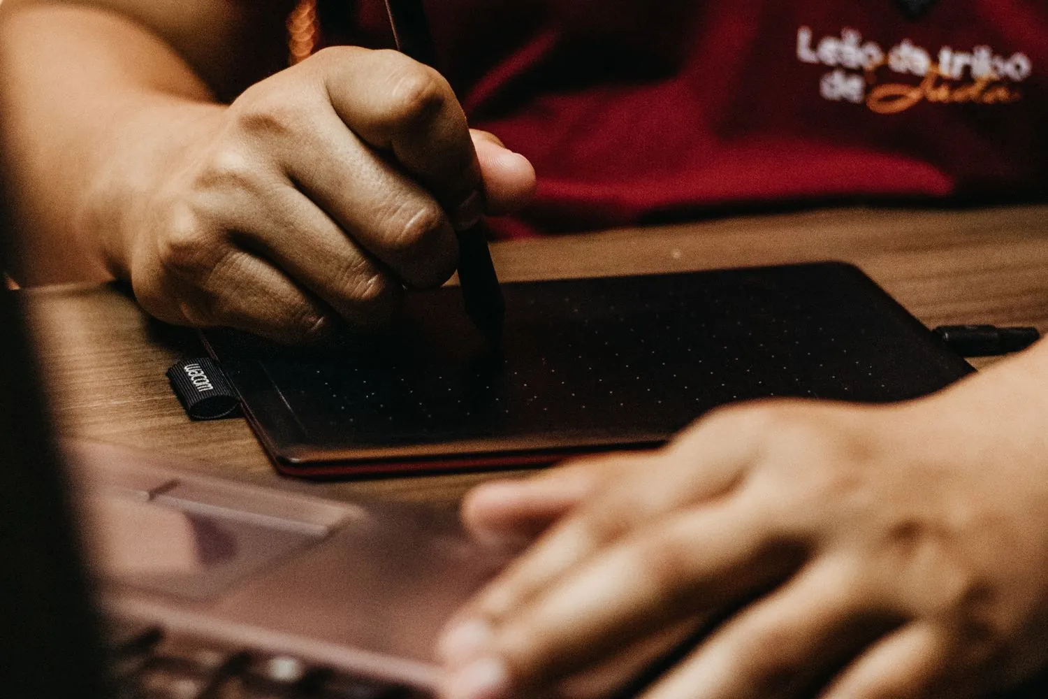 Designer utilisant une tablette graphique et un stylet devant un écran d'ordinateur